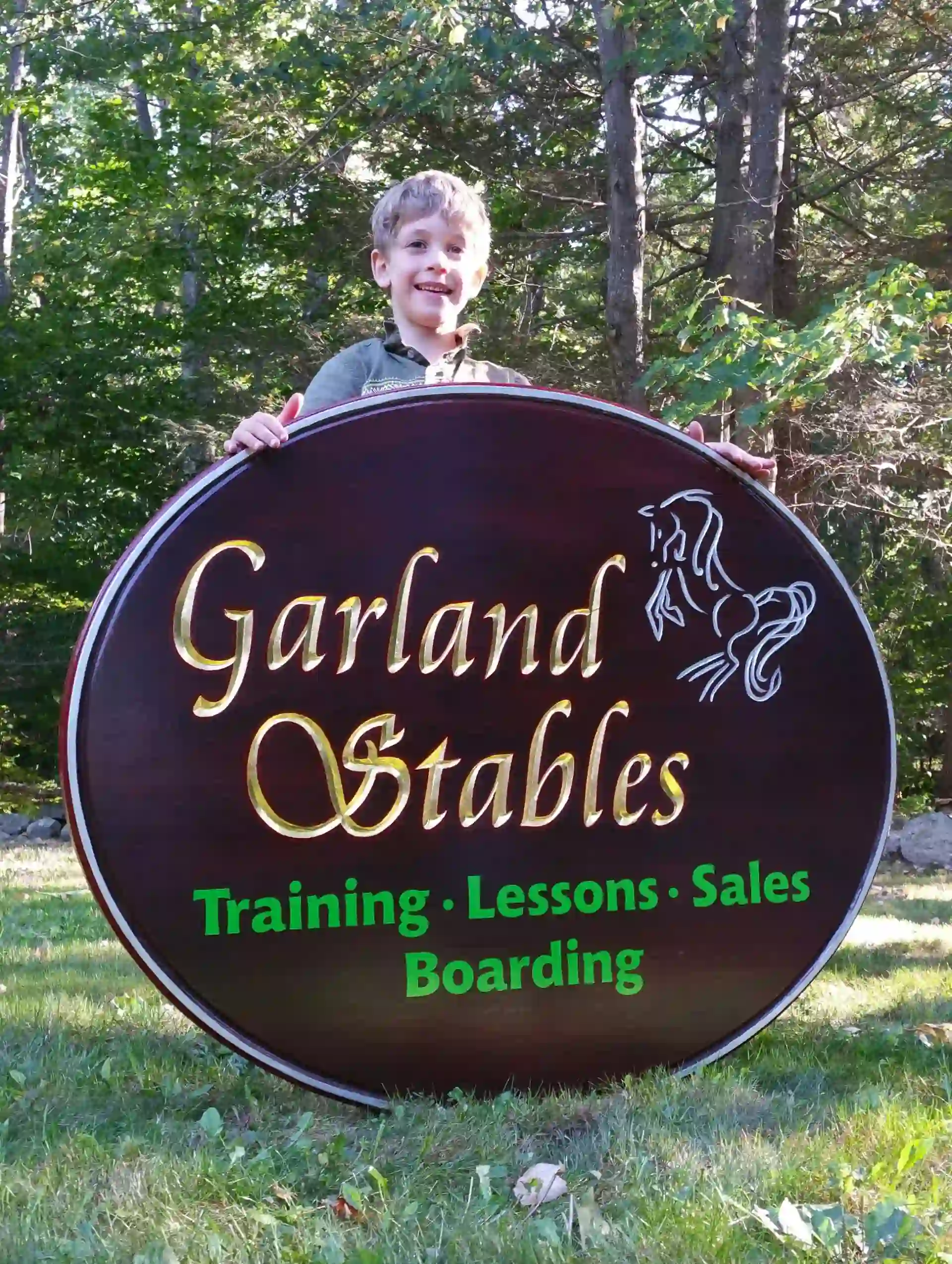Carved oval Garland Stables sign with gold-leaf lettering